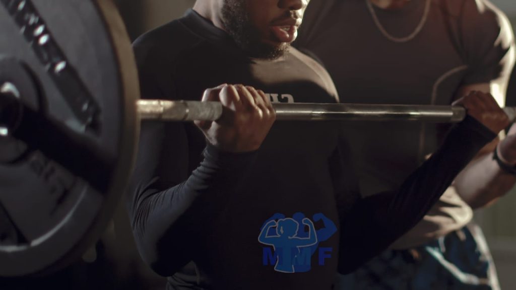 Black man performing barbel curls with a spotter.