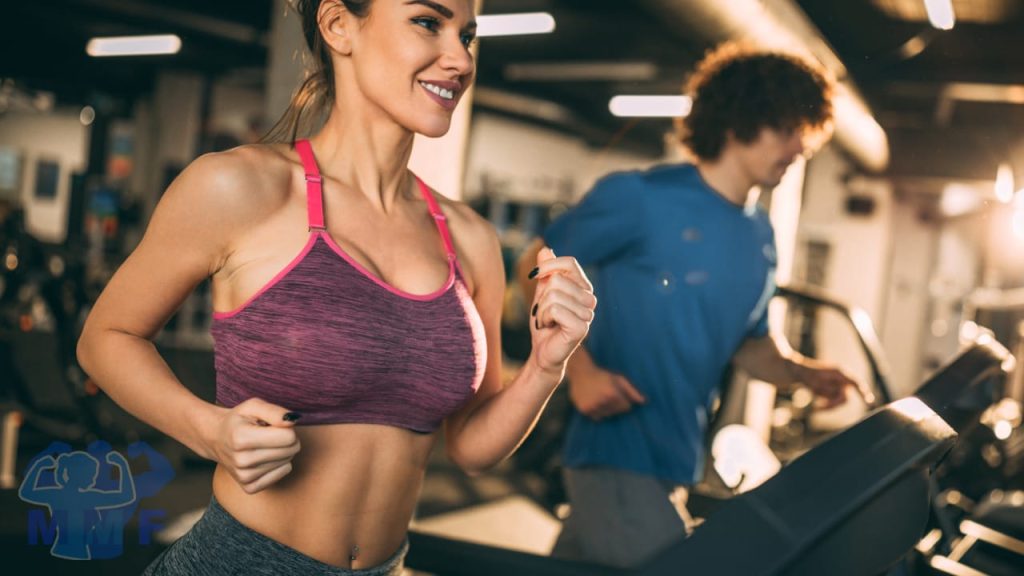 Beautiful fit woman in the foreground and man in the background on treadmills discussing the importance of aerobic exercise.